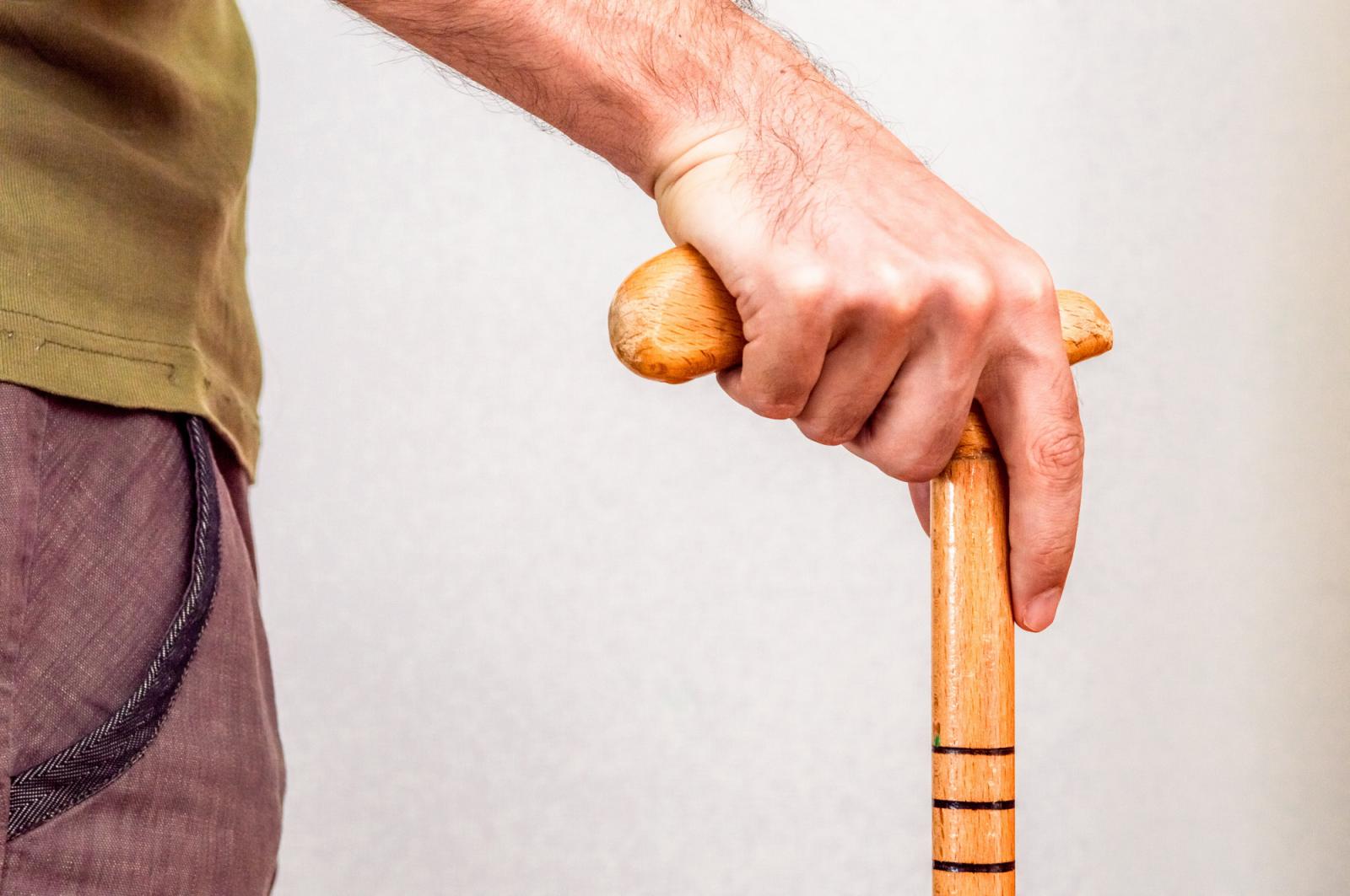 Image of a man with his hand on a walking stick.