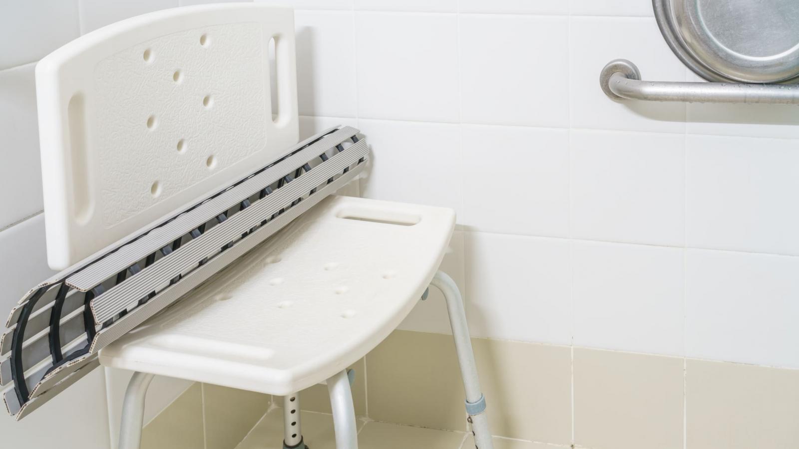Image of shower chair in shower with nonslip mat on it and grab bar on wall